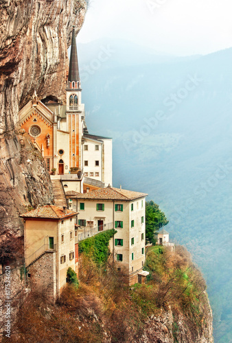 Stone steps of stairs to Ancient Madonna della Corona santuario facade under rocks in high mountains, Veneto region, Italy, famous touristic landmark