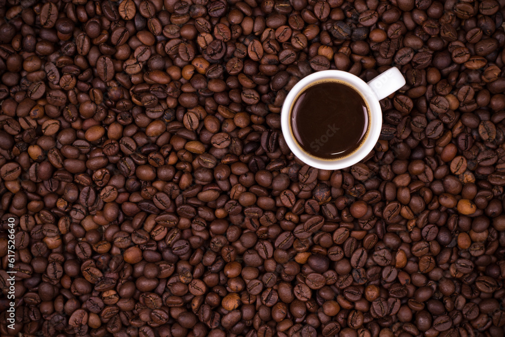 Roasted coffee beans background with white coffee cup Roasted coffee beans background with white coffee cup