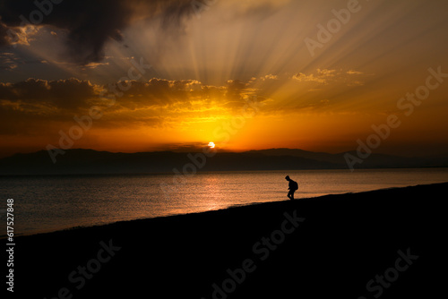 Woman walking by the shore at sunset