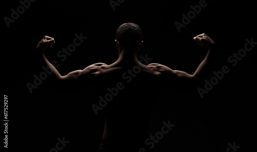 strong athletic mans back isolated on black background