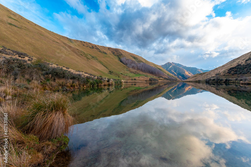 Photograph of Lake Kirkpatrick with mountains reflecting in the water on a cloudy day outside Queenstown on the South Island of New Zealand photo