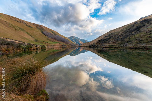 Photograph of Lake Kirkpatrick with mountains reflecting in the water on a cloudy day outside Queenstown on the South Island of New Zealand photo