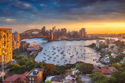 Cityscape image of Sydney, Australia with Harbour Bridge and Sydney skyline during sunset.