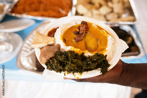 foreground of traditional western cameroon food, taro with yellow sauce served at the table, traditional african dish from western cameroon. photo
