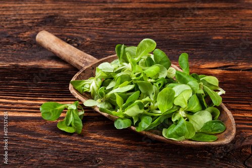 Foto Fresh green field salad on old wooden spoon on rustic vintage wooden background