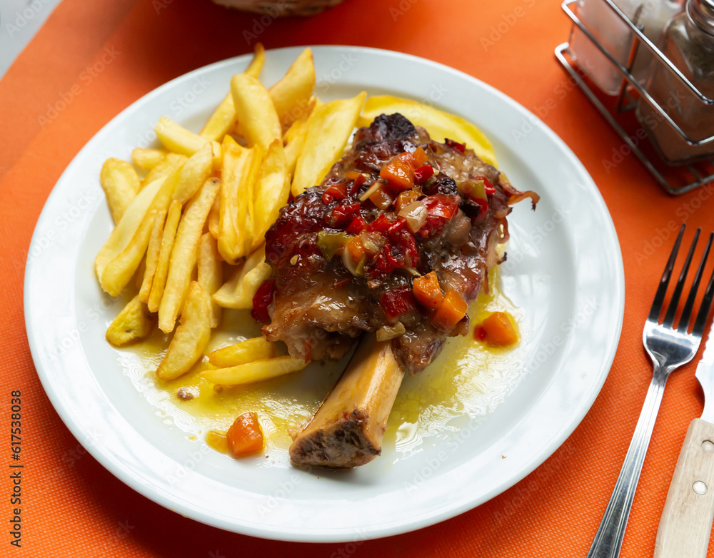 Image of pork baked shank with vegetables and french fries served at plate