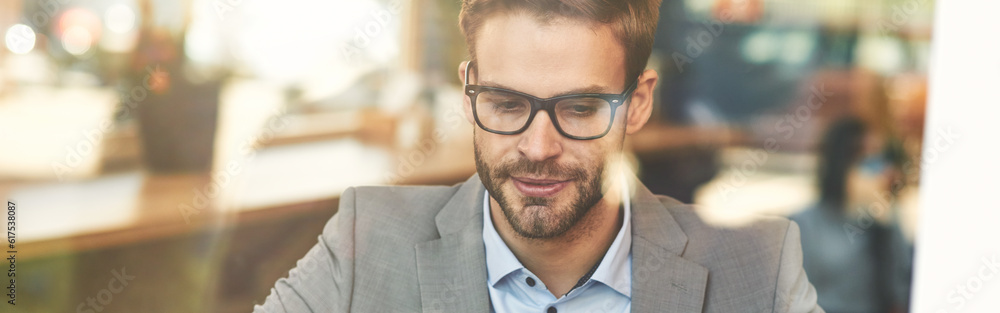 Front view of a young busy caucasian businessman or male freelancer using laptop while working remotely in cafe