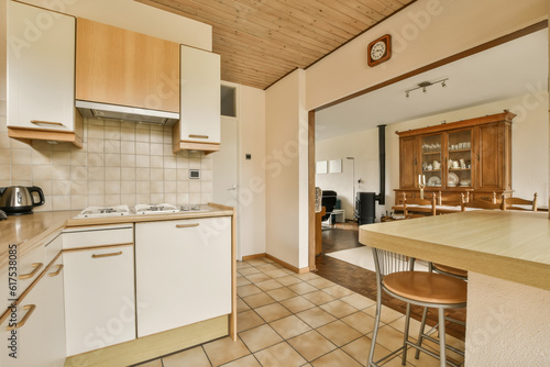 a kitchen and dining area in a small apartment with wood paneled ceilings  tile flooring and white cabinets