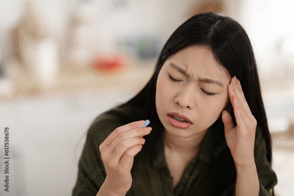 Closeup of unhappy young asian woman taking painkiller Closeup of unhappy young asian woman taking painkiller