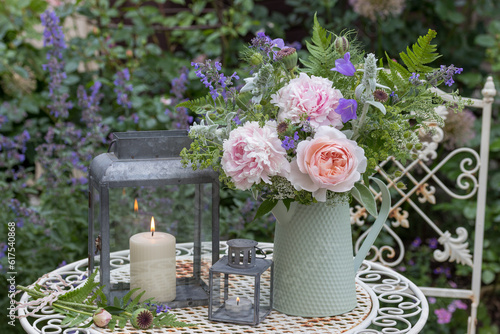 romantisches Arrangement mit Blumenstrauß mit Rose, Pfingstrosen und Sommerblumen und vintage Laternen photo