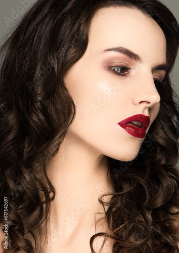 Beauty red lips makeup fashion model curly hair on grey background in warm tones