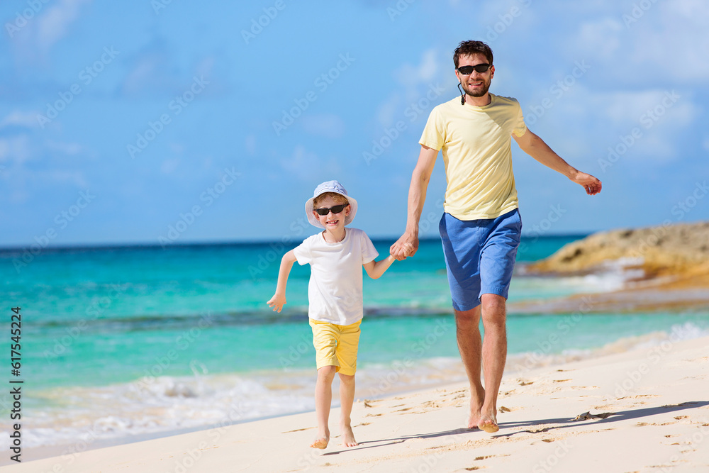 happy family of two, father and son, running and enjoying summer vacation together at perfect caribbean beach
