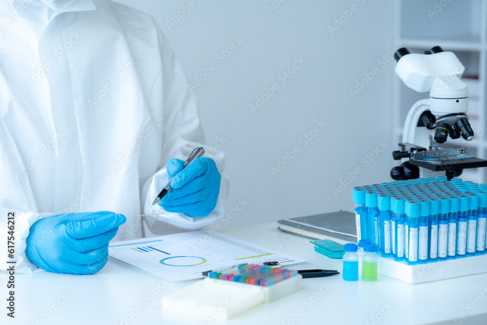 Doctor hand taking a blood sample tube from a rack with machines of analysis in the lab background, Technician holding blood tube test in the research laboratory. Doctor hand taking a blood sample tube from a rack with machines of analysis in the lab background, Technician holding blood tube test in the research laboratory.