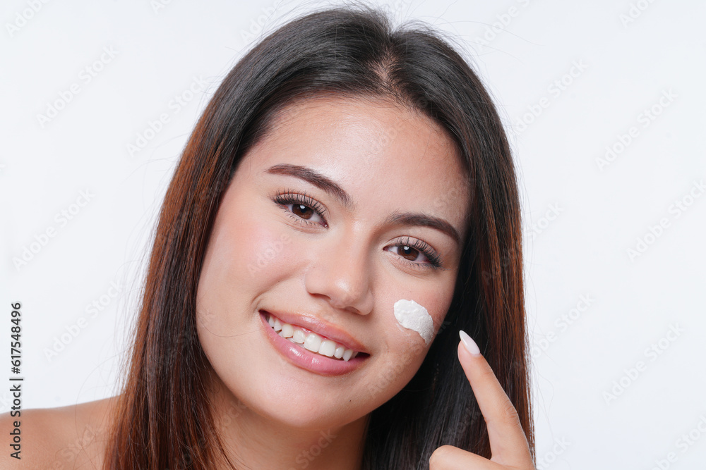 Naklejka premium Portrait of a beautiful young woman applying moisturizer to her skin