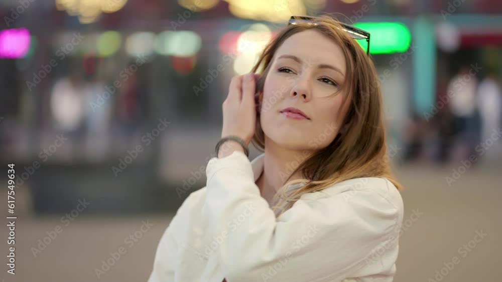 A thoughtful young girl sits on the street with numerous lighting of light banners, straightening her hair A thoughtful young girl sits on the street with numerous lighting of light banners, straightening her hair