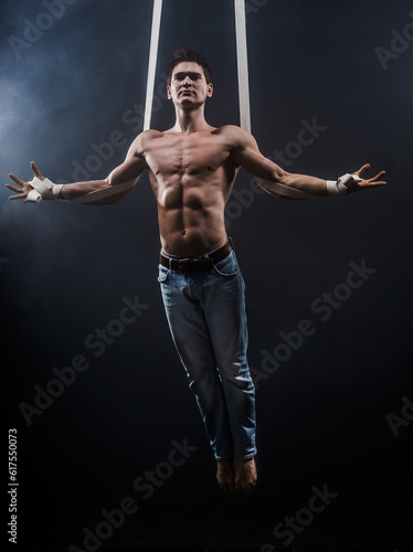 circus artist on the aerial straps with Strong muscles on black background © Designpics