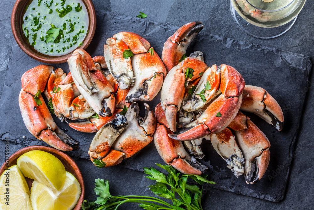 Seafood. Crabs tentacles on black plate with wite wine, lemon and herbs sauce on slate background. Top view Seafood. Crabs tentacles on black plate with wite wine, lemon and herbs sauce on slate background. Top view