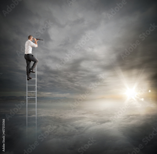 Businessman on a ladder high into the sky watching with binoculars
