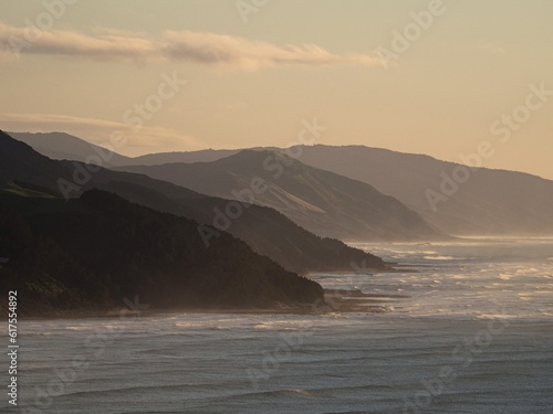 Colorful pastel sky sunrise view of mountain silhouette layered seaside hills at Castle Point, Wellington New Zealand © Marc
