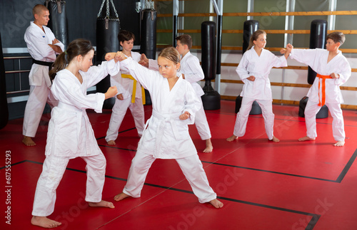 Two preteen girls working in pair, mastering new karate moves in class