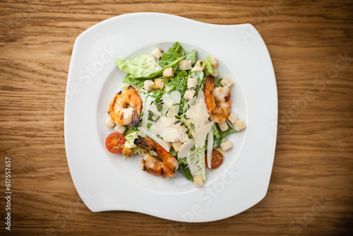 Caesar Salad with shrimps served on a plate in restaurant