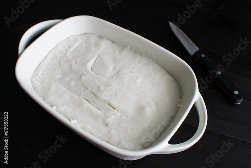 Set and Sliced Hawaiian Coconut Pudding (Haupia) in a Small Dish: Chilled coconut pudding sliced into small squares with a paring knife