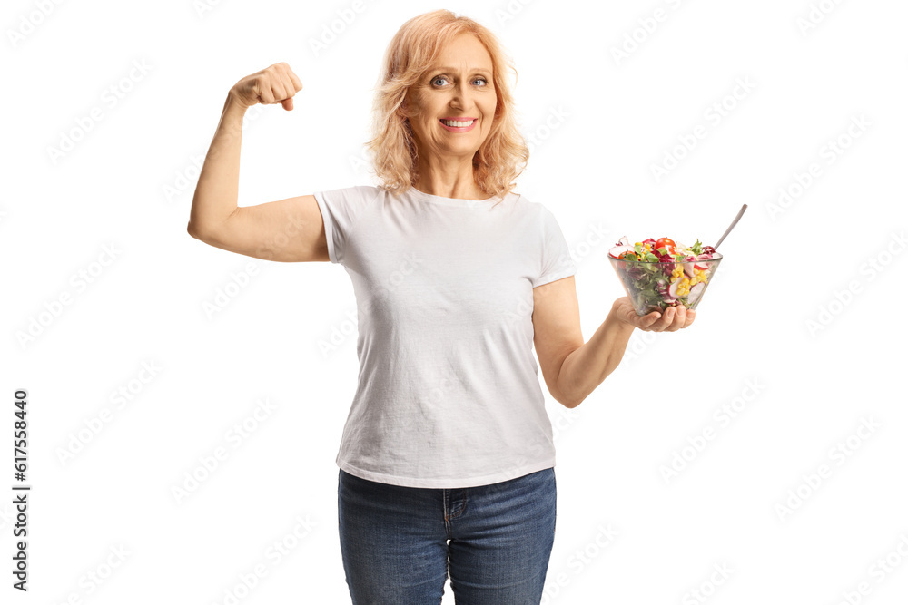 Mature woman holding a salad and showing strong muscle Mature woman holding a salad and showing strong muscle