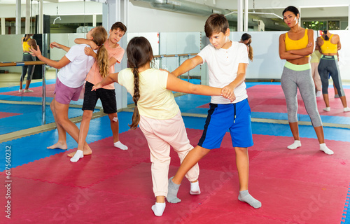 Sporty girls and boys are practices self-defence moves in pairs in sporty gym