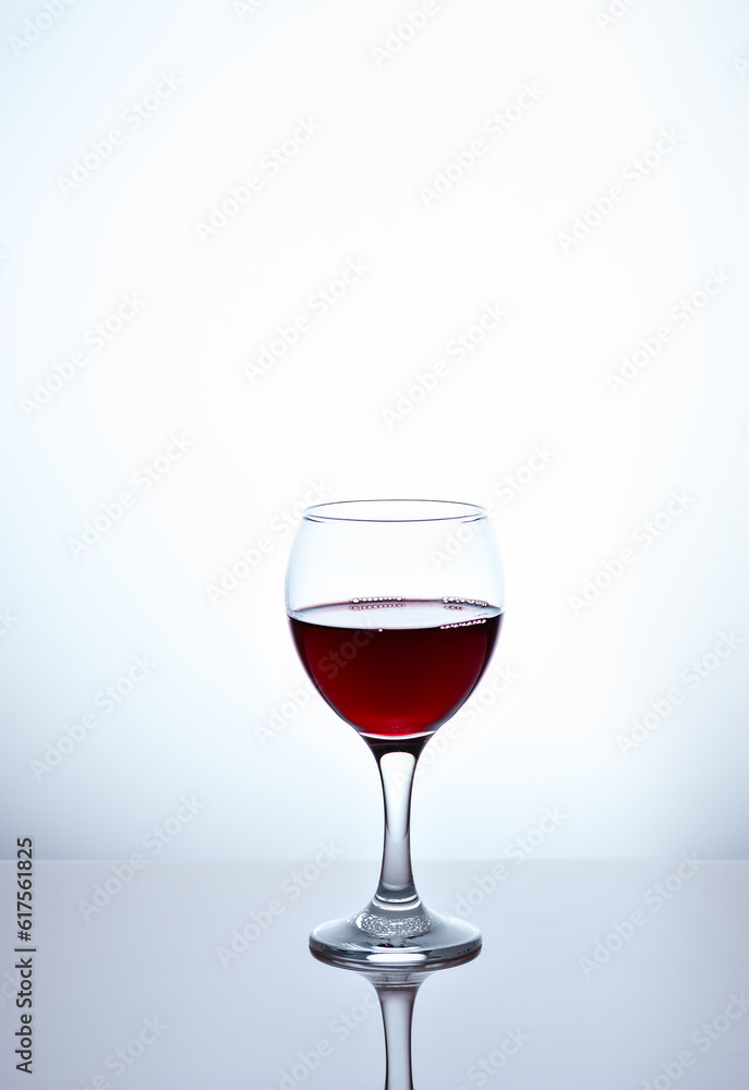 One glass filled with half red wine One glass filled with half red wine