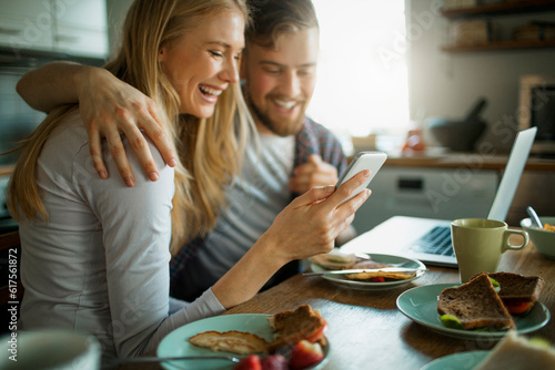 Young couple having breakfast in the morning and using their smart phone