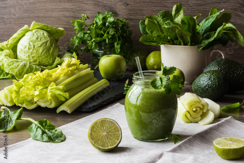Detox diet. Green smoothie with different vegetables on wooden background.