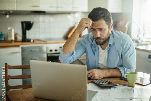 Young man going over his home finances in the kitchen