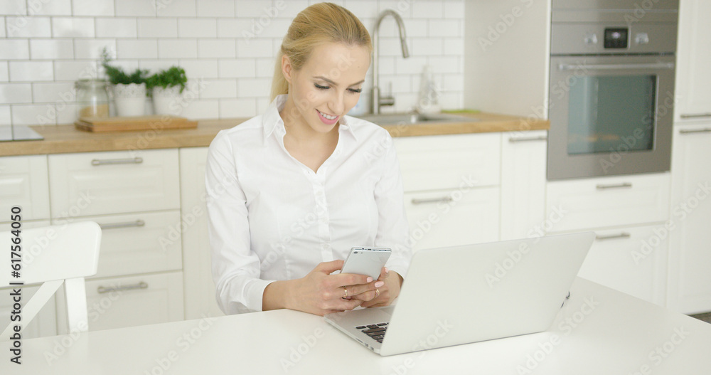 Young wonderful woman wearing white shirt and using while sitting at table with laptop at kitchen. Young wonderful woman wearing white shirt and using while sitting at table with laptop at kitchen.