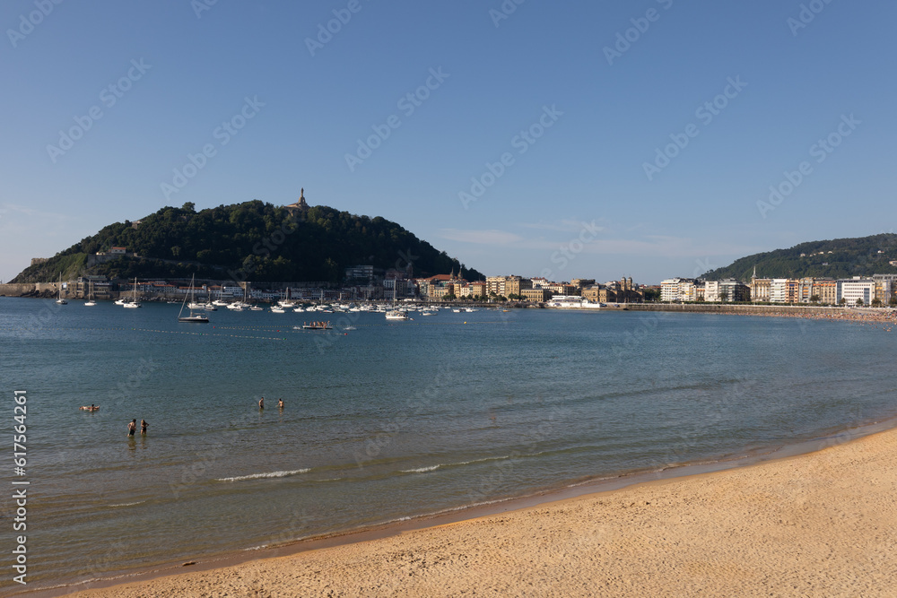 sandy beach shore with blue sea in the bay with mountain in the background in Spain