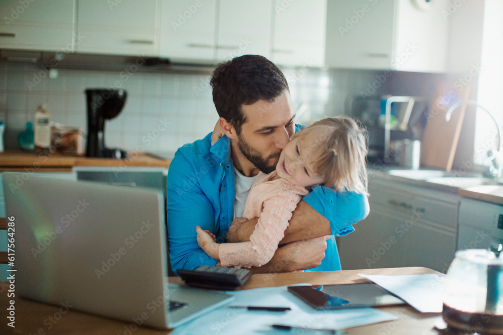 Single father going over the bills with his daughter in the lap Single father going over the bills with his daughter in the lap