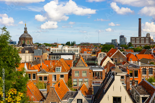 View from above of historic center of Dutch city of Leiden on sunny day overlooking typical townhouses with terracotta tiled gabled roofs, dome of St. Mary church and power station at background.. photo