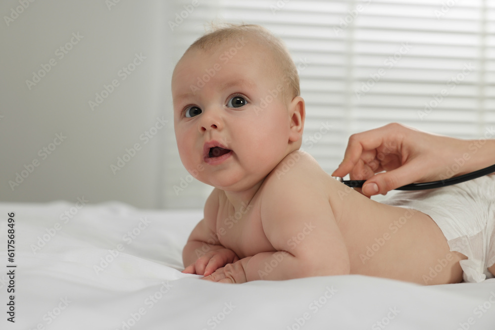 Pediatrician examining cute little baby with stethoscope in clinic, closeup Pediatrician examining cute little baby with stethoscope in clinic, closeup