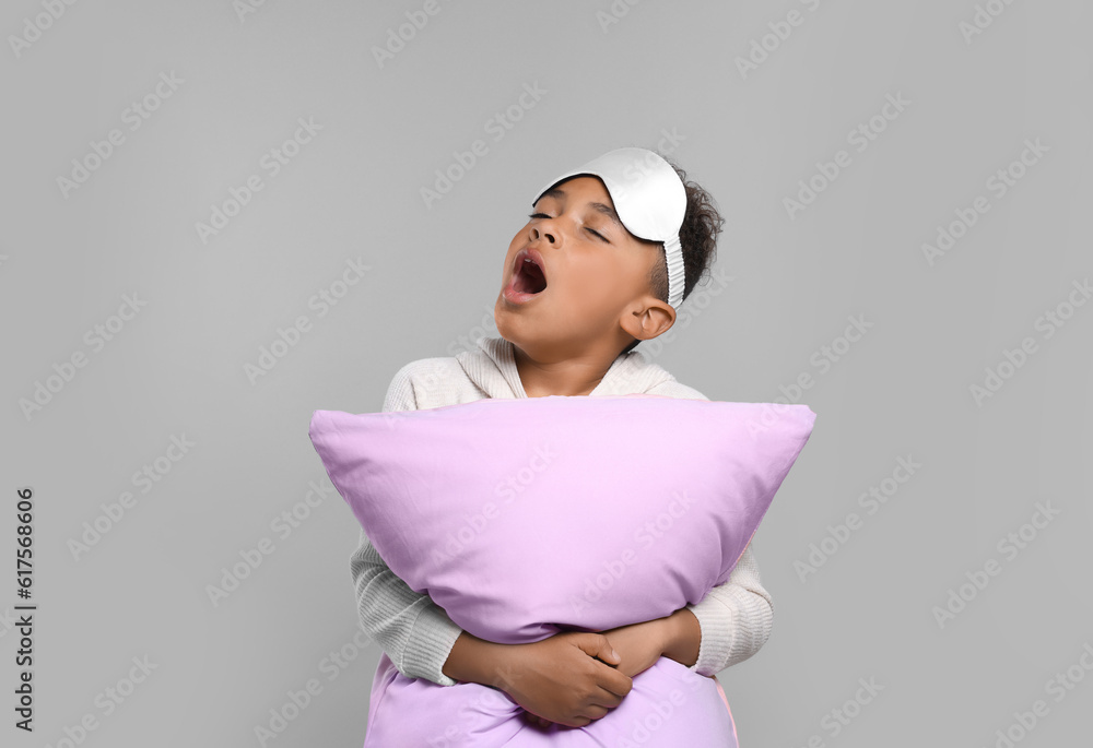 Boy with pillow and sleep mask yawning on grey background. Insomnia problem Boy with pillow and sleep mask yawning on grey background. Insomnia problem