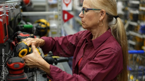 Mature woman looking at sander and power tools at a large hardware store.