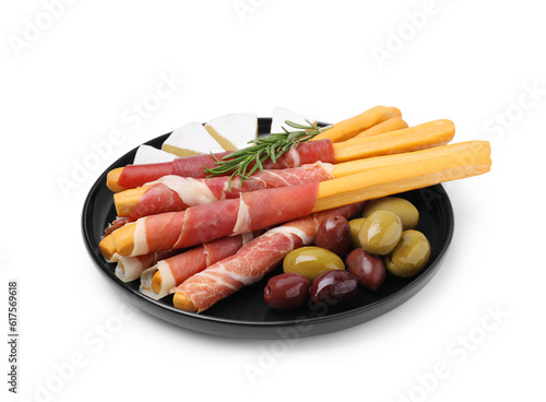 Plate of delicious grissini sticks with prosciutto, cheese and olives on white background