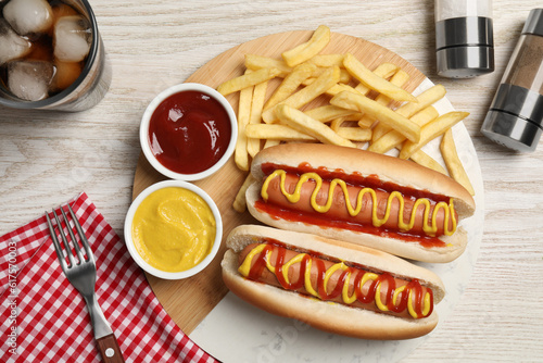 Delicious hot dogs with mustard, ketchup and potato fries on white wooden table, flat lay