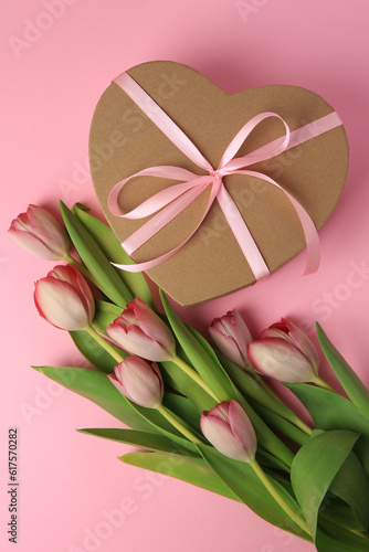 Heart shaped gift box with bow and beautiful tulips on pale pink background, flat lay © New Africa
