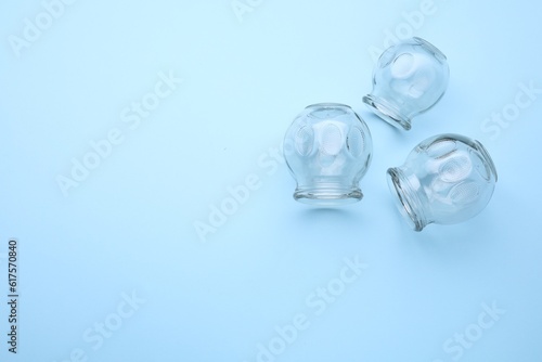 Glass cups on light blue background  flat lay with space for text. Cupping therapy