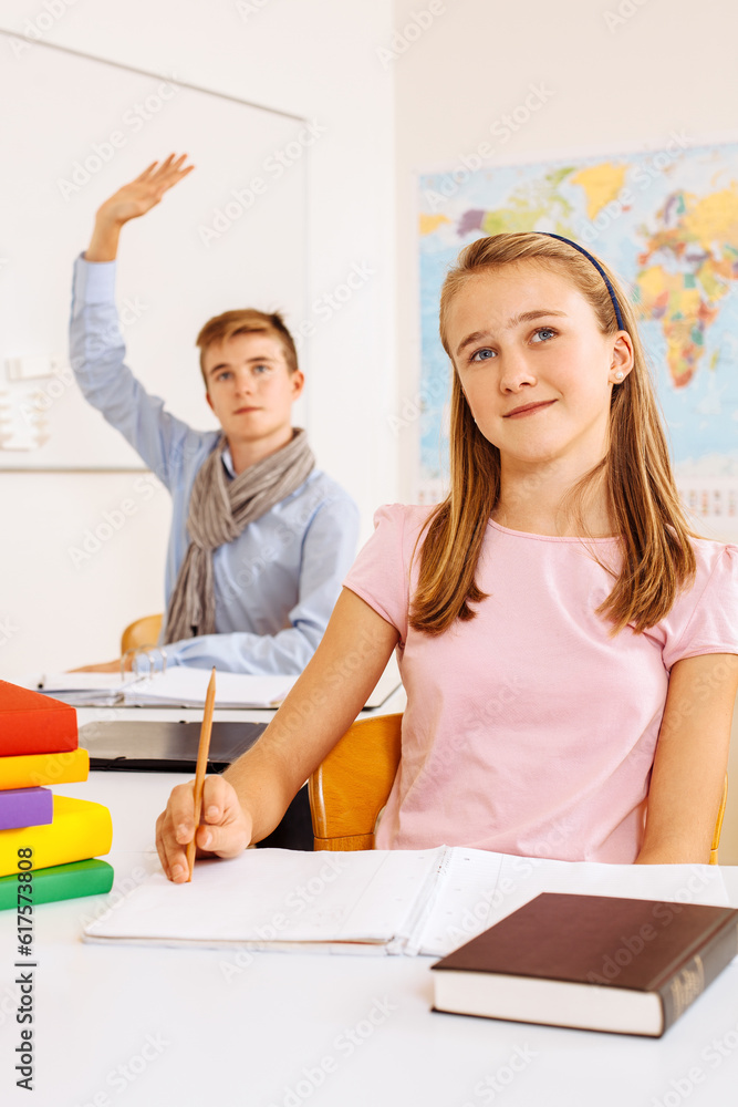 Obraz premium Photo of two teenagers in a classroom happy and lifting their hands to answer a question.