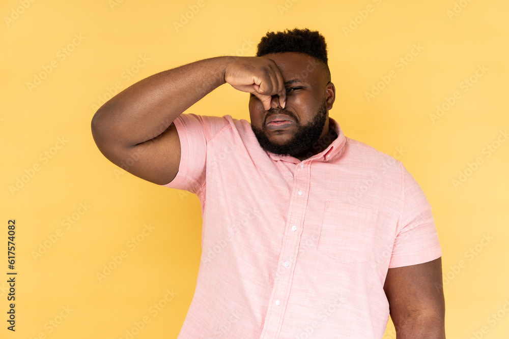What is a bad small? Portrait of man pinching nose, stop breathing bad odor, disgusted by smell of farting, expressing repulsion, gross. Indoor studio shot isolated on yellow background. What is a bad small? Portrait of man pinching nose, stop breathing bad odor, disgusted by smell of farting, expressing repulsion, gross. Indoor studio shot isolated on yellow background.