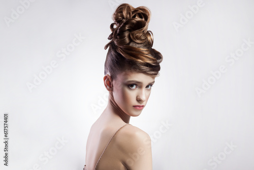 Portrait of attractive brunette young brown haired woman with stylish hairdo and makeup looking at camera with serious confident face. Indoor studio shot isolated on gray background.