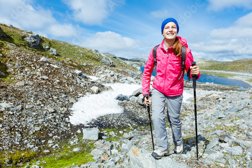 Happy hiking girl with trekking sticks in the mountains. Norway