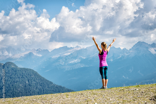 young woman on top of the mountain with the arms raised
