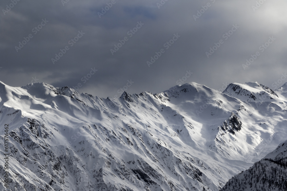 High snowy mountains and sunlight storm sky in evening. Caucasus Mountains. Svaneti region of Georgia. High snowy mountains and sunlight storm sky in evening. Caucasus Mountains. Svaneti region of Georgia.