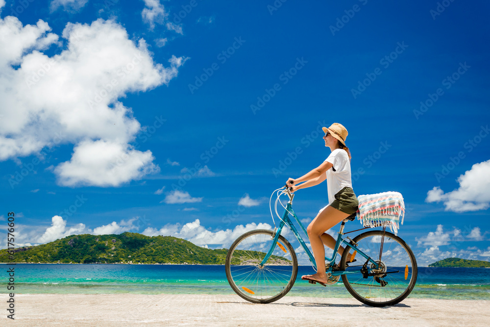 Fototapeta premium Woman on a bicycle ride along The Beach at Seychelles